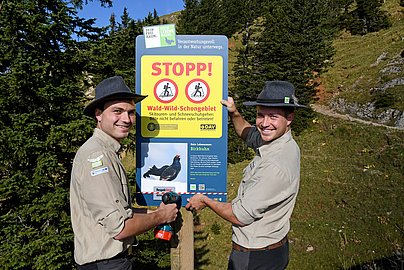 Zwei Ranger im Naturpark Nagelfluhkette beim Aufstellen eines Schildes.