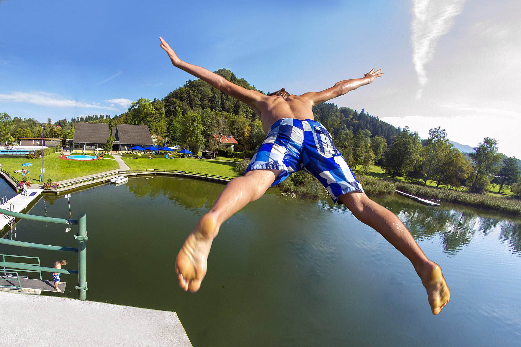 Ein Junge springt vom Springturm ins Wasser im Freibad Kleiner Alpsee.