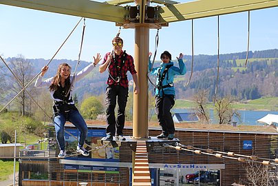 Drei Besucher klettern auf dem Alpsee Skytrail in Bühl am Großen Alpsee.