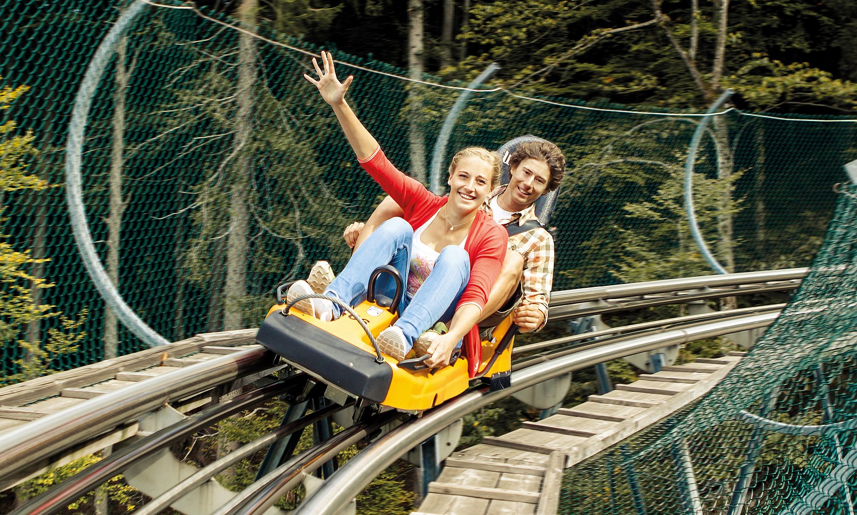 Zwei junge Erwachsene fahren den Alpsee Coaster der Alpsee Bergwelt in Immenstadt.