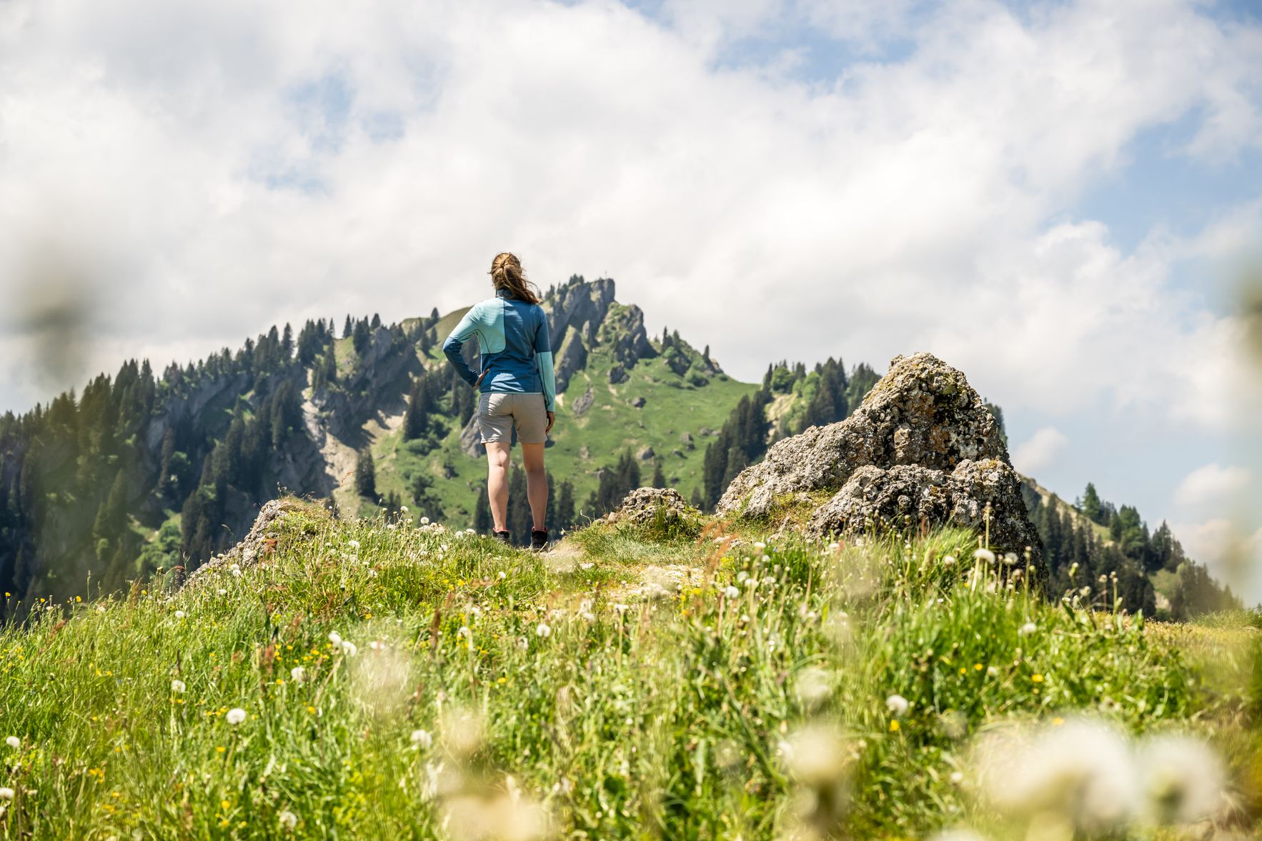 Eine Frau steht auf dem Wanderweg und blickt in Richtung des Steinebergs. Der Berg ist Teil des Naturparks Nagelfluhkette.
