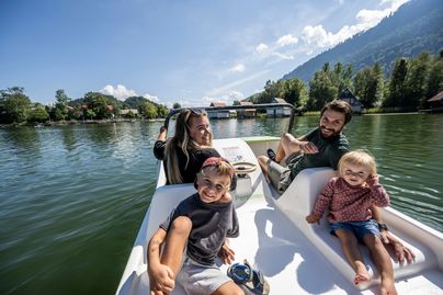 Eine Mama und ein Papa fahren gemeinsam mit ihren zwei Kindern über den großen Alpsee in Immenstadt.