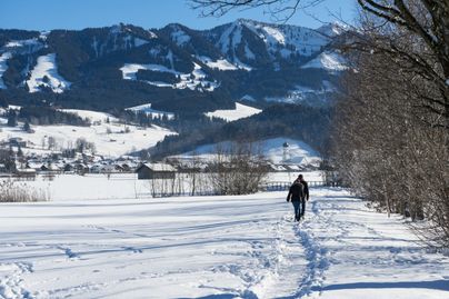 Ein paar wandert im Winter auf einem Winterwanderweg in Richtung Altstädten (Sonthofen)