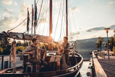 Ein schöner Segelboot im Hafen bei Sonnenuntergang. Die ruhige Atmosphäre und die umliegende Natur schaffen eine entspannende Stimmung.