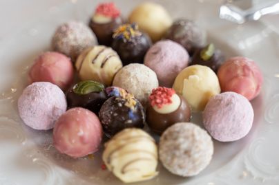 Eine Auswahl an köstlichen Pralinen in verschiedenen Farben und Geschmäckern. Sie sind kunstvoll dekoriert und attraktiv auf einem Teller angeordnet.