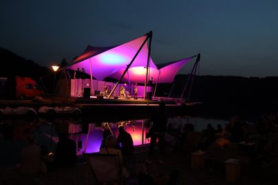 Eine Band spielt abends auf der Seebühne am Großen Alpsee auf dem Outdoorfestival Allgäu 2023.