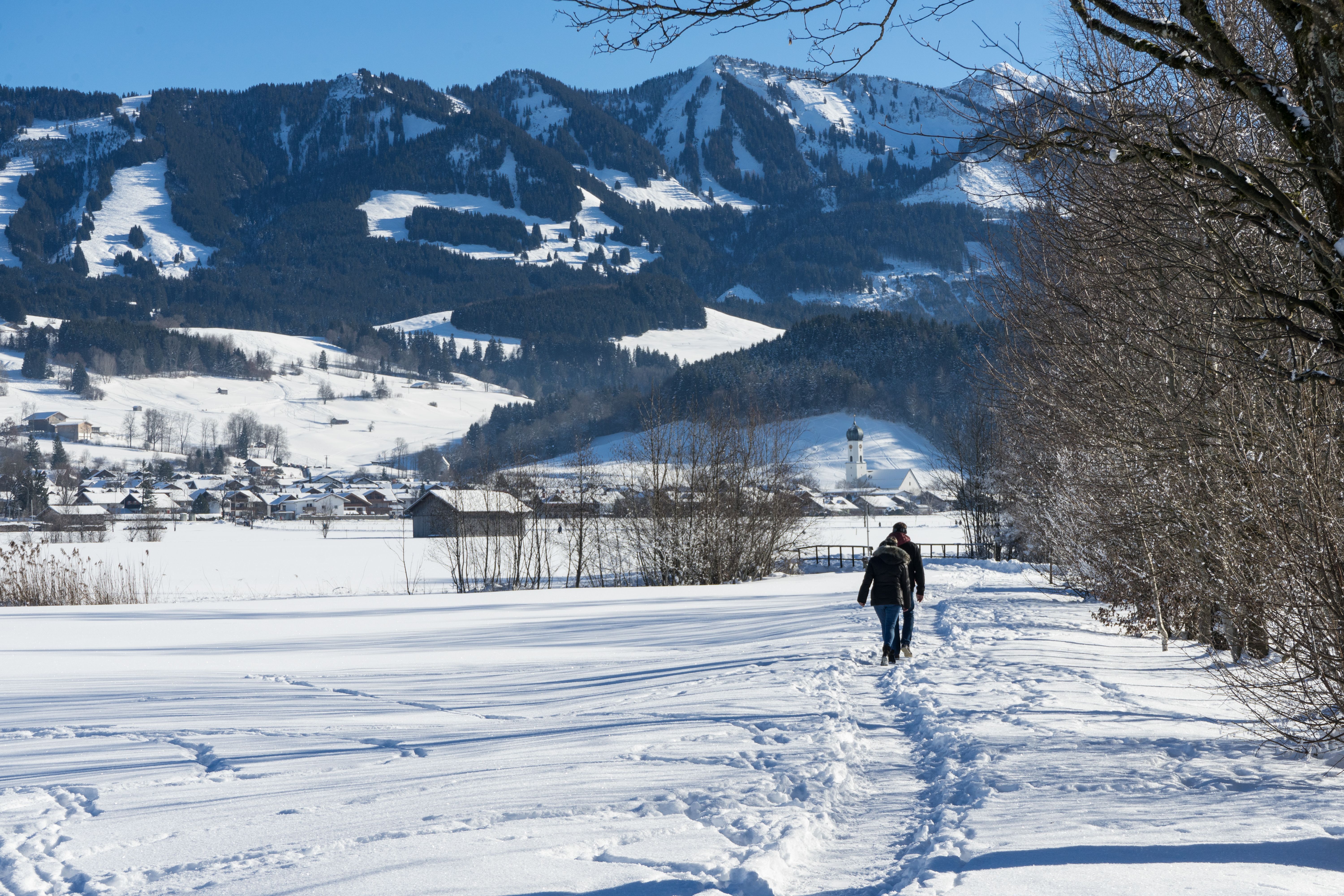 Ein paar wandert im Winter auf einem Winterwanderweg in Richtung Altstädten (Sonthofen)
