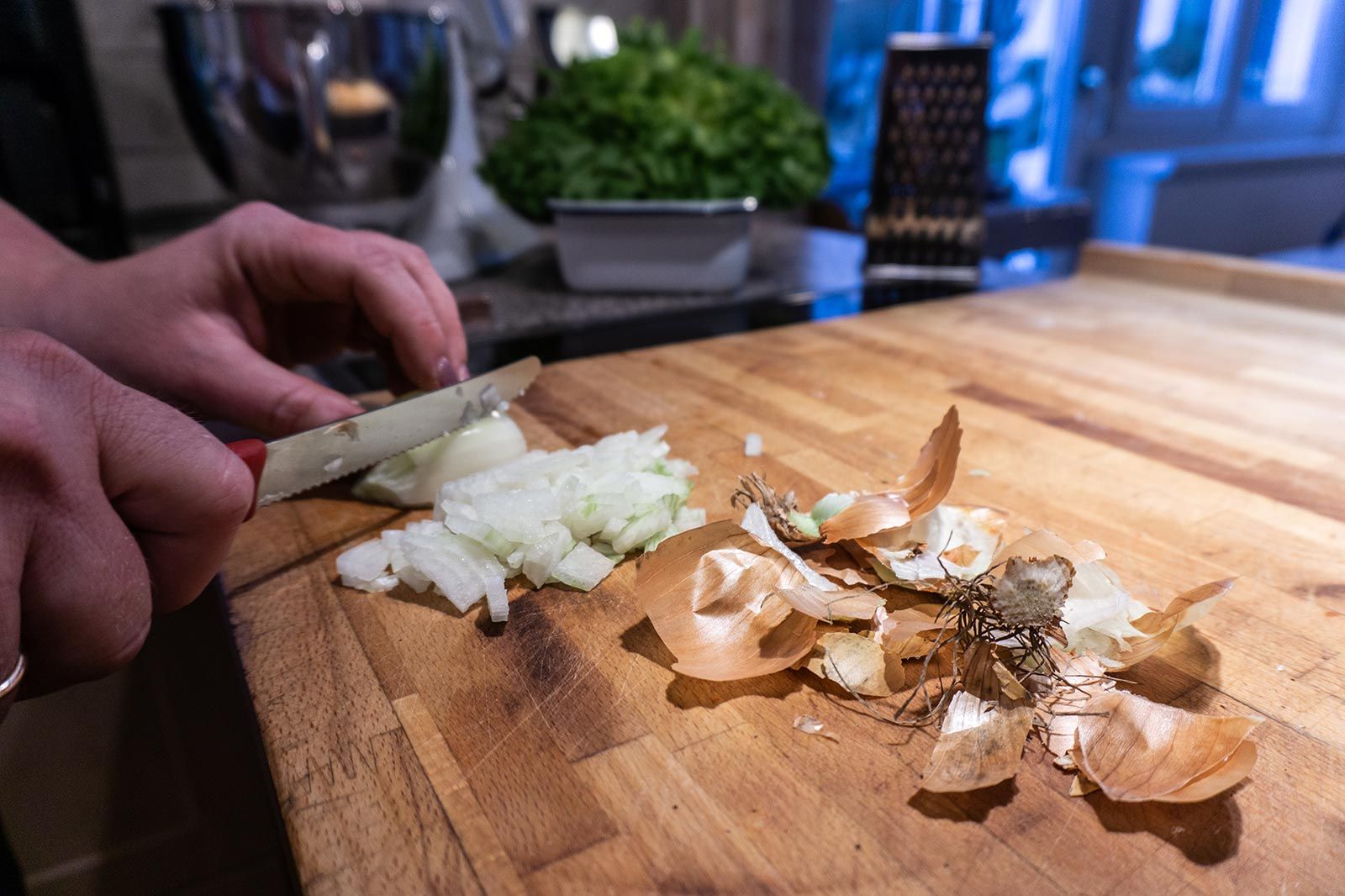 Für die Zubereitung der Allgäuer Kässpatzen werden Zwiebeln in grobe Stücke geschnitten.