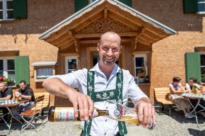 Der Wirt vom Gasthof Hirsch in Vorderburg (Rettenberg) schenkt demonstrativ einen "Weizen" - ein typisches bayerisches Biergetränk ein. Das besondere am Gasthof Hirsch ist, dass dieser durch die Dorfgemeinschaft Vorderburg finanziert und betrieben wird, um den Dorfmittelpunkt und die Gastronomie im Ort zu erhalten.