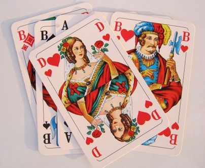 Ein Satz Spielkarten mit einer Dame und einem König in farbenfrohem Design. Die Karten zeigen Symbole und Zahlen in roten und schwarzen Farben.