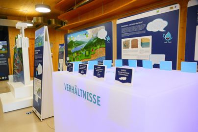 Eine moderne Ausstellung mit interaktiven Displays und Informationspaneelen zum Thema Umwelt. Der Raum ist gut beleuchtet und ansprechend gestaltet.