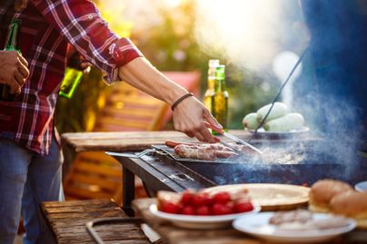 Eine Grillparty im Garten mit saftigem Fleisch und frischen Beilagen. Im Hintergrund sind Getränke und eine entspannte Atmosphäre zu sehen.