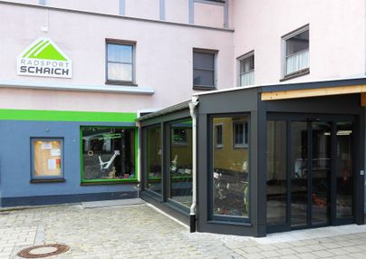 Ein Fahrradladen mit der Aufschrift "Radsport Schich". Der Eingangsbereich ist modern gestaltet mit großen Fenstern und einer hellen Fassade.