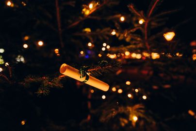 Detailaufnahme von einem Tannenbaum mit einem Wunschzettel am Zweig.