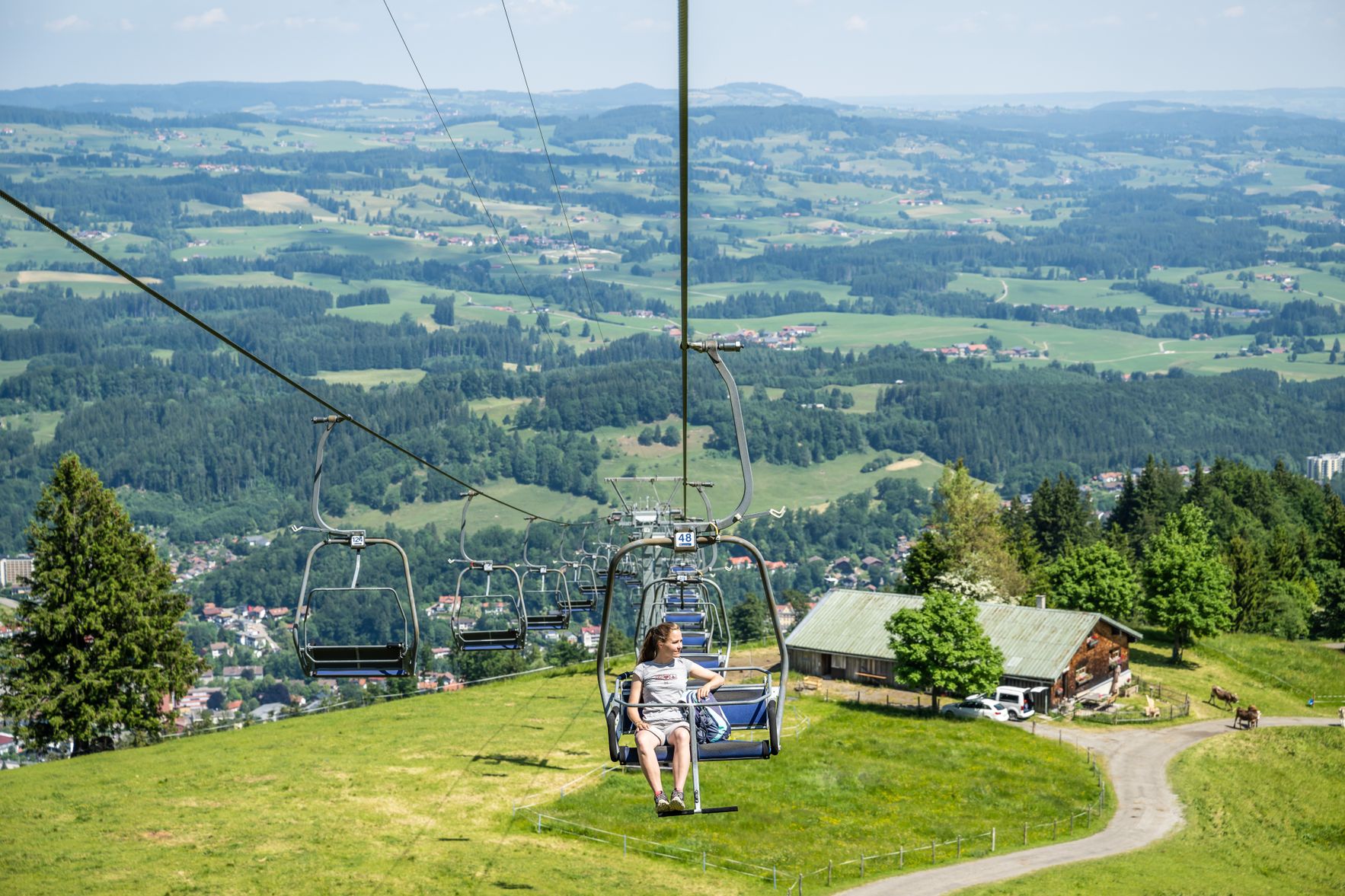 Eine Frau sitzt im Doppelsessel der Mittagbahn in Immenstadt und fährt Richtung Mittaggipfel.
