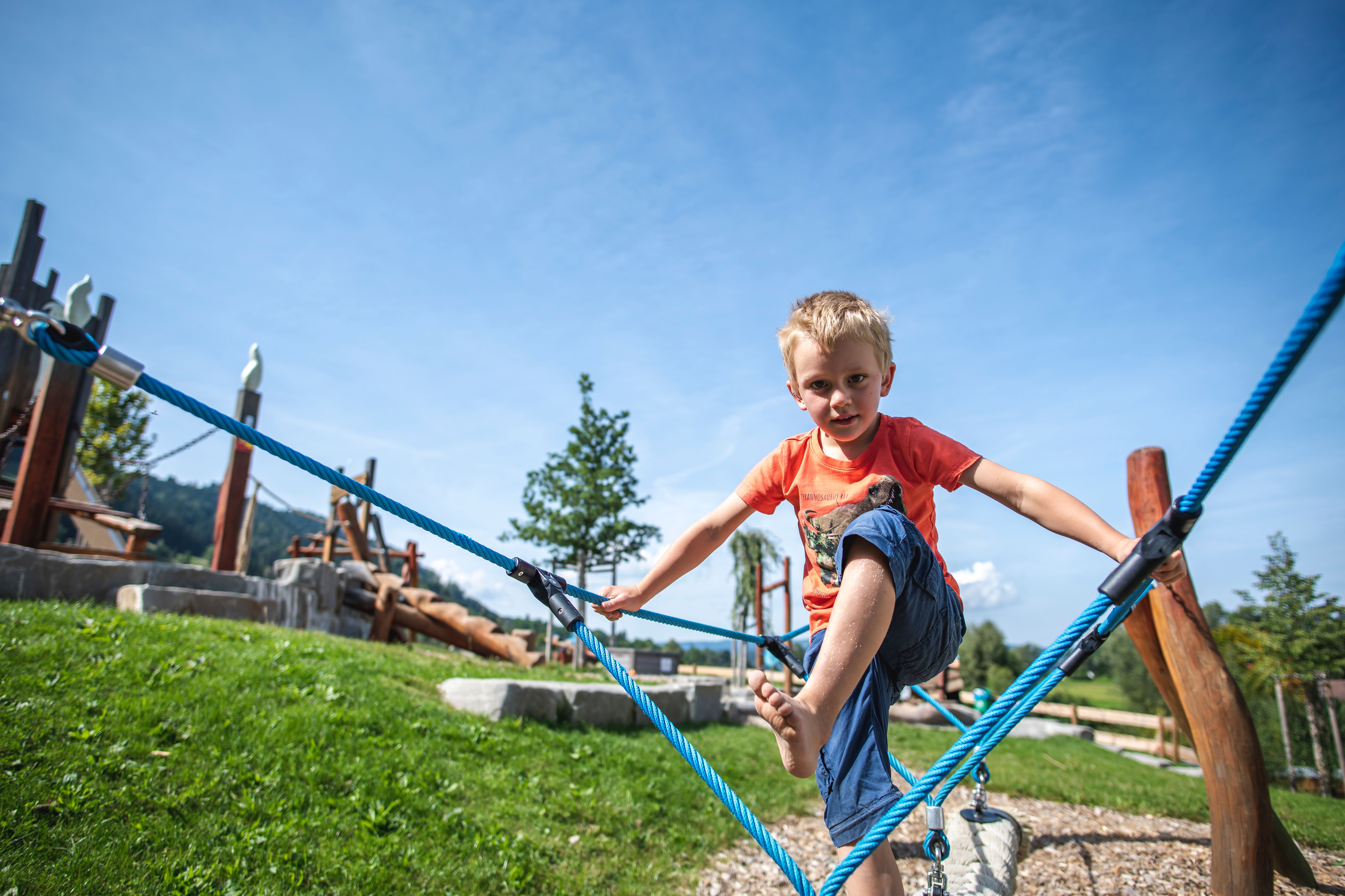Ein Junge klettert entlang eines Seils auf dem Spielplatz in Ettensberg (Blaichach)