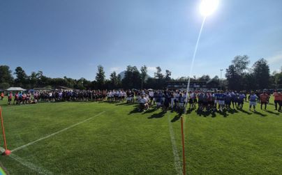 Eine Versammlung von Menschen auf einem Sportfeld unter klarem Himmel. Viele Teilnehmer stehen in Gruppen, um an einem Event teilzunehmen.