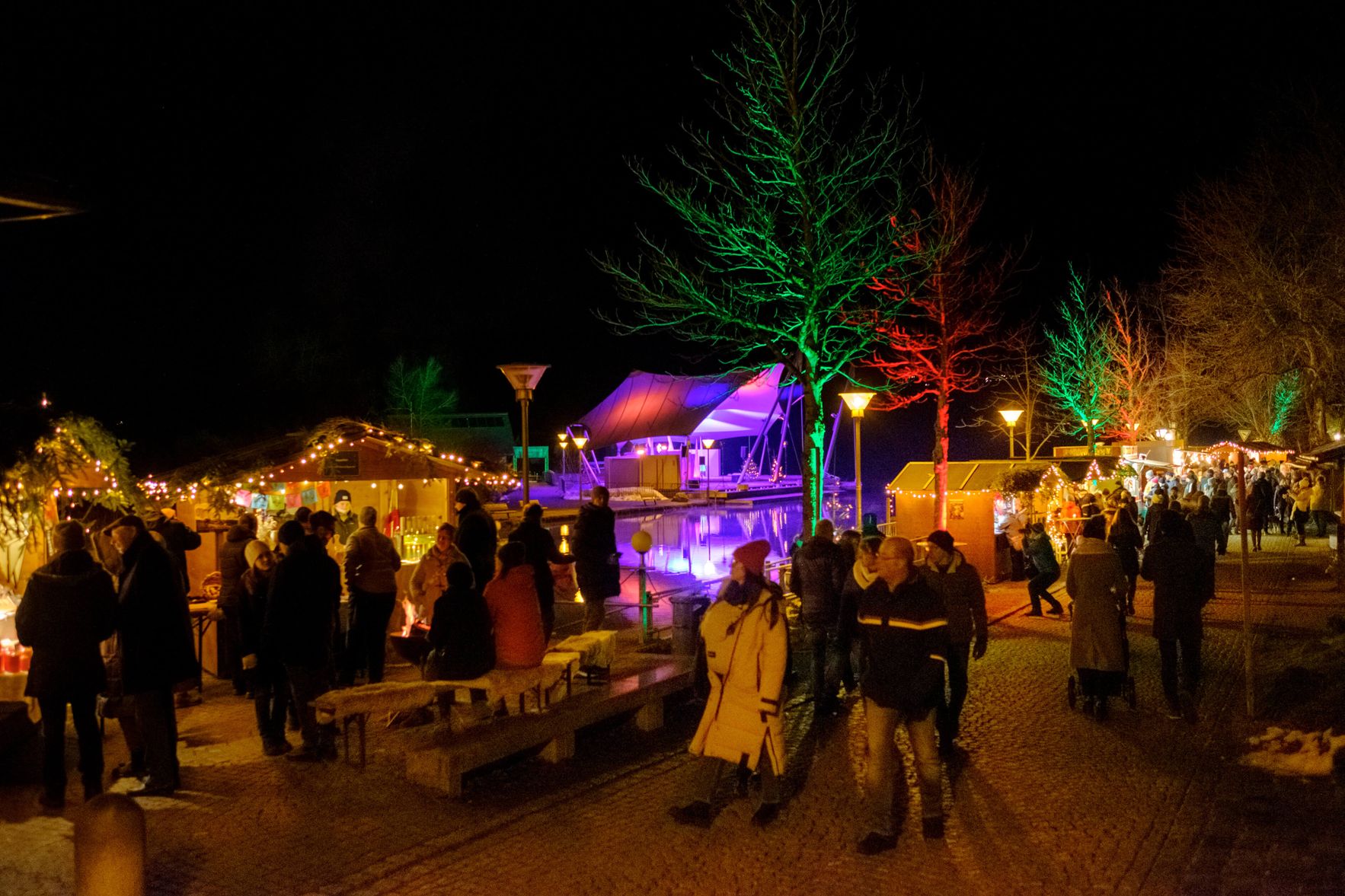 Uferpromenade am Grossen Alpsee bei Immenstadt bei Nacht und mit Besuchern und beleuchteten Ständen an der Seeweihnacht.