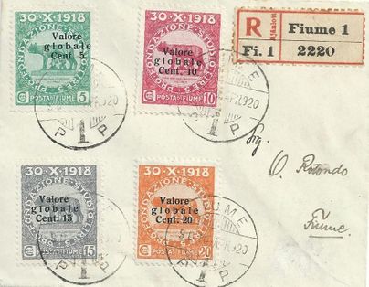 Eine alte Postkarte mit vier verschiedenen Briefmarken und einem roten Einschreiben-Stempel. Die Briefmarken sind in unterschiedlichen Farben und Werten, datiert am 30. Oktober 1918.