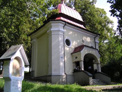 Ein hübsches Bauwerk mit einer roten Dachkuppel steht umgeben von grünen Bäumen. Die Fassade ist hell und die Architektur wirkt einladend.