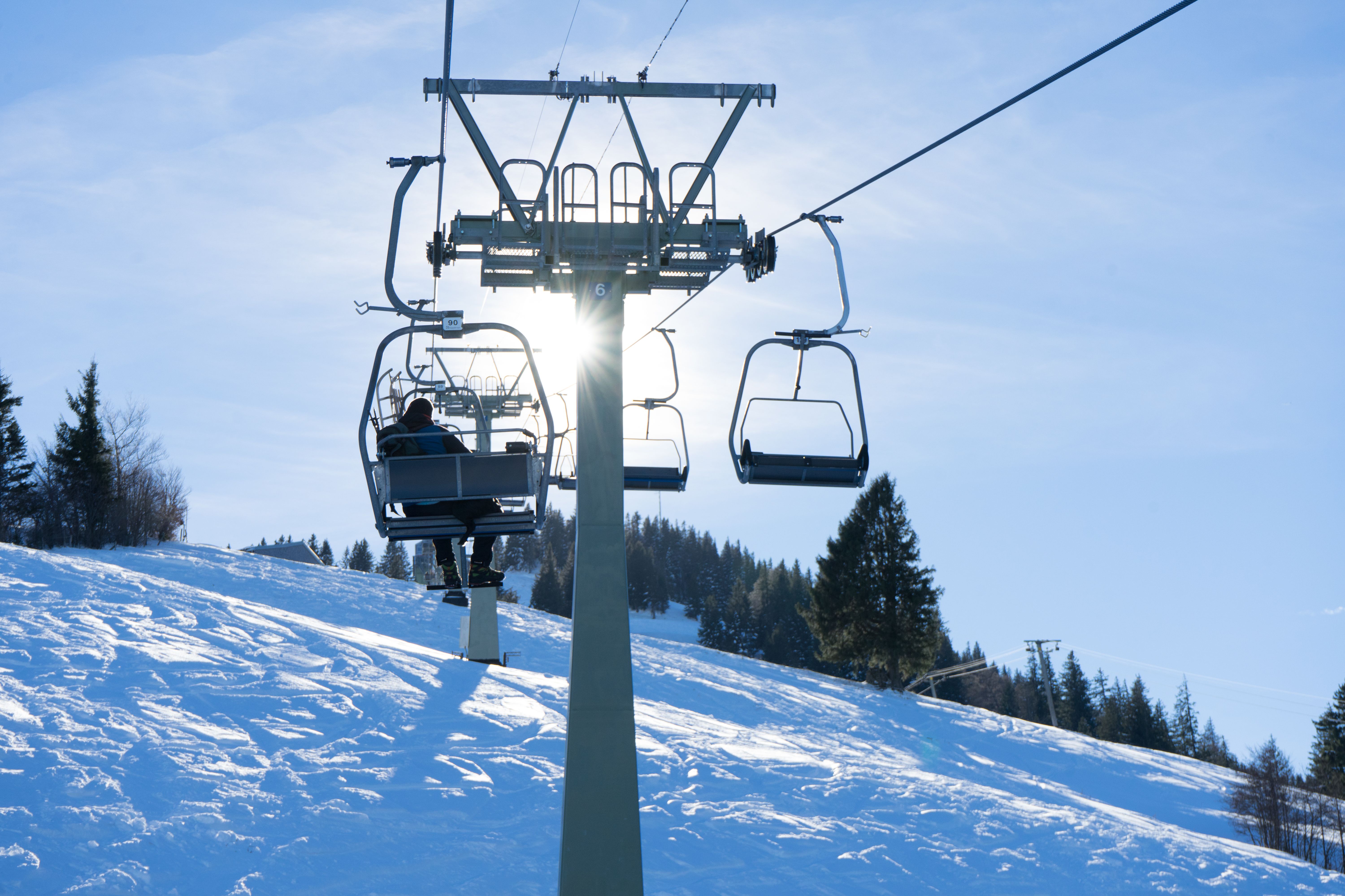 Ein Mann sitzt im Winter im Doppelsessel der Mittagbahn und fährt nach oben. Der Mittagberg in Immenstadt eignet sich im Winter mit seiner fünf Kilometer langen Naturrodelbahn sehr gut zum Rodeln.