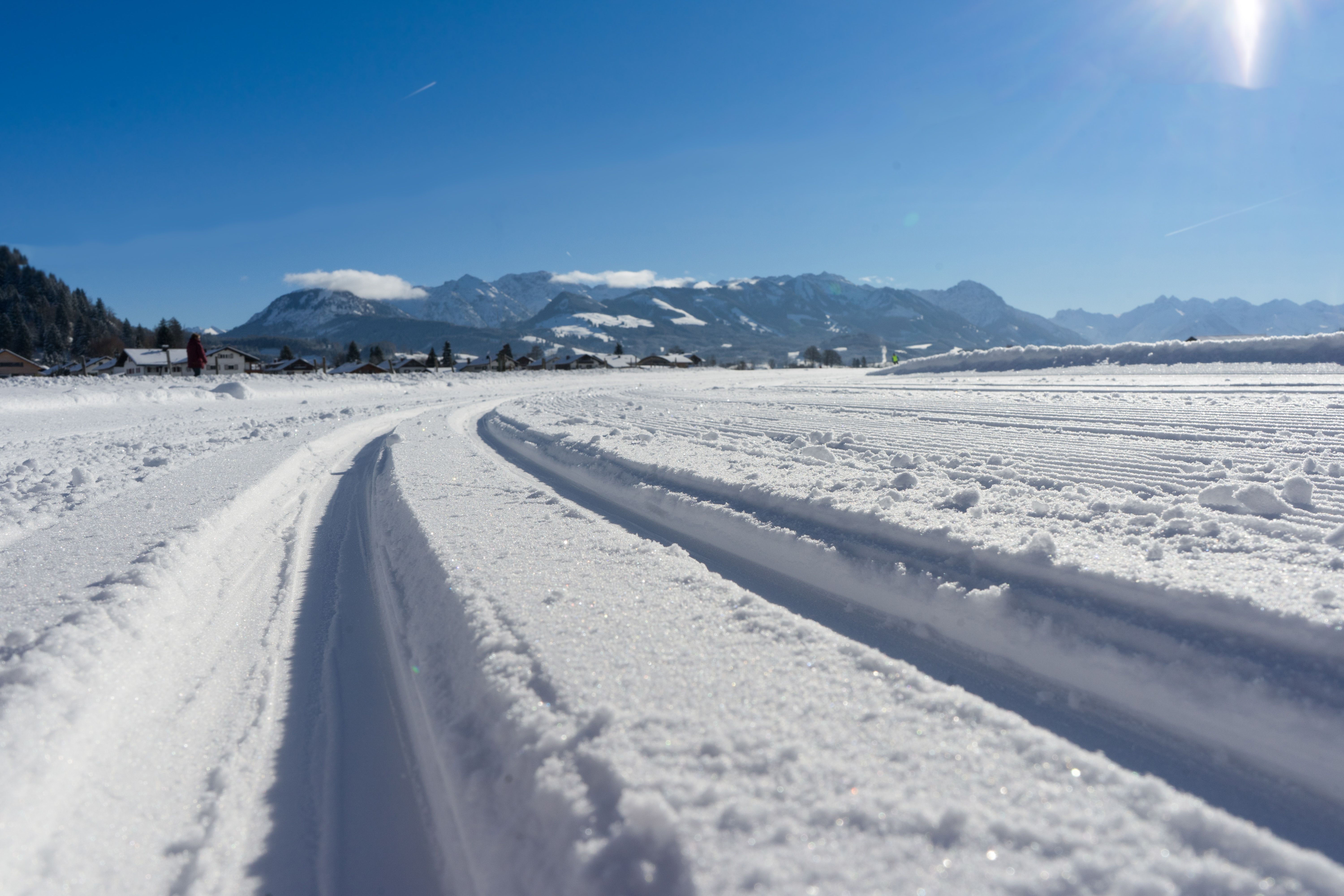Eine Langlaufloipe in Burgberg vor Bergpanorama. Eine Reise nach Burgberg lohnt sich im Winter besonders für Winterwanderer, Schneeschuhgeher und Langläufer auf gut präparierten Wegen und Loipen.