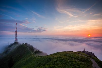Die Sonne geht hinter dem Sendemast auf dem Grünten unter.