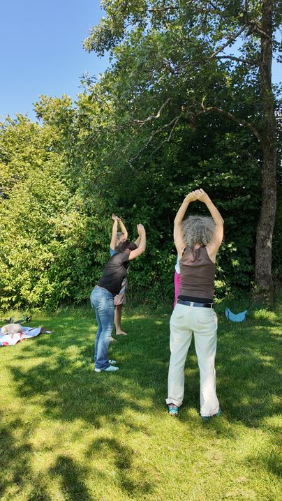 Eine Gruppe von Menschen beim Lachyoga auf der großen Liegewiese im Rahmen der Urlaubswochen im Städtle 