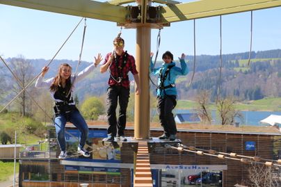 Drei Besucher klettern auf dem Alpsee Skytrail in Bühl am Großen Alpsee.
