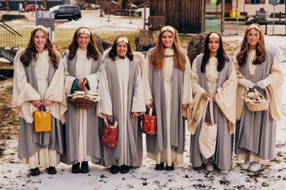 Sechs junge Frauen verkleidet als Engel mit Geschenken in den Händen.