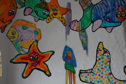 Bunt gemalte Unterwasserwesen hängen von der Decke. Es gibt Sterne, Fische und Quallen, die fröhlich aussehen.