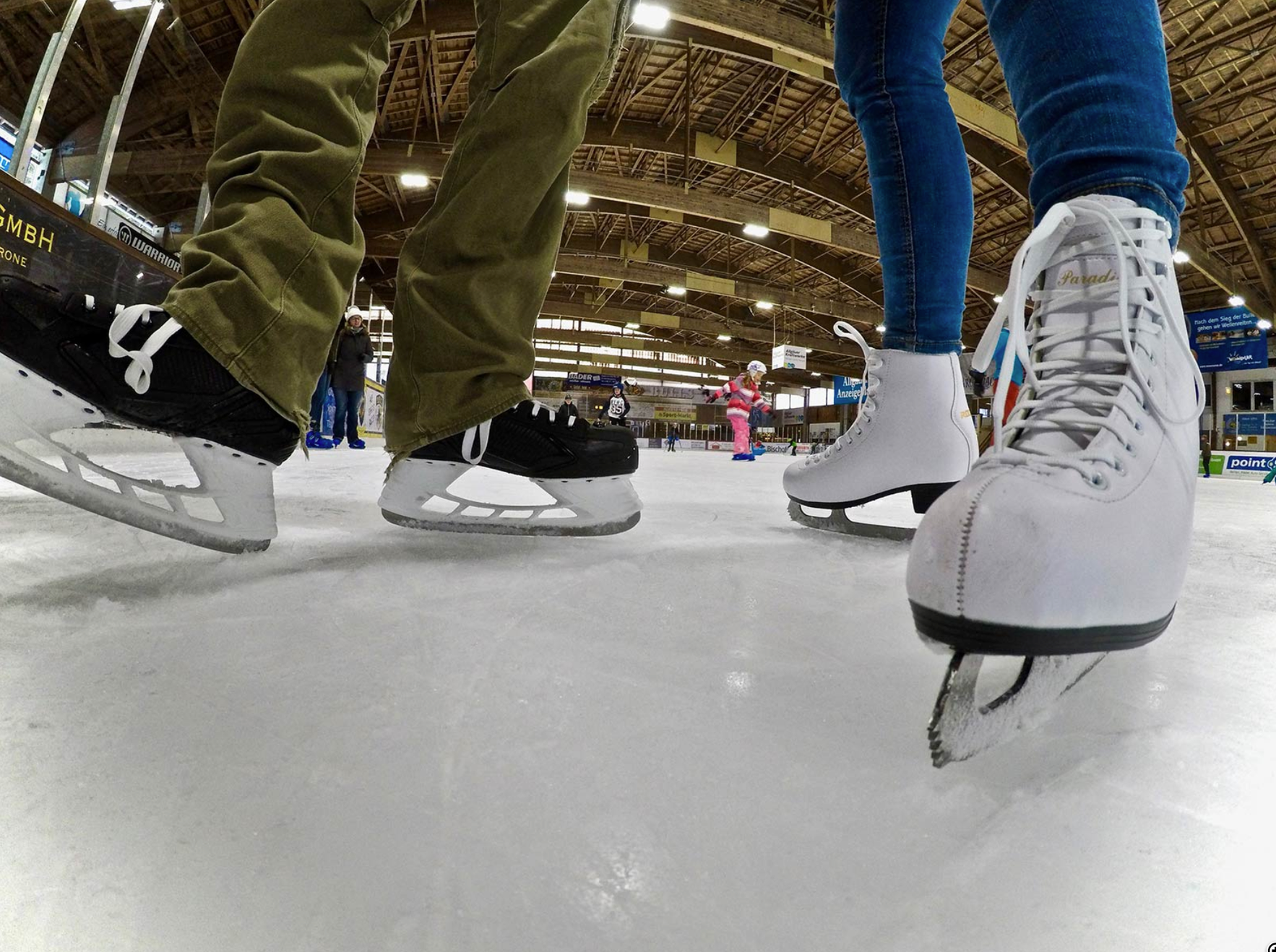 Auf der frisch präparierten Eisbahn gleiten zwei paar Schlittschuhe in der überdachten Eisporthalle in Sonthofen.