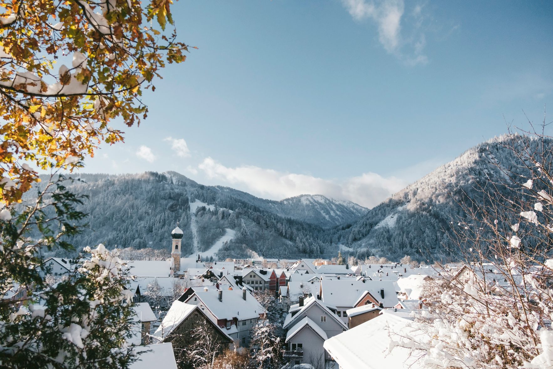 Das Bild zeigt die Stadt Immenstadt mit der Stadtpfarrkirche St. Nikolaus im Winter. Im Hintergrund sind die Berge des Naturparks Nagelfluhkette zu sehen