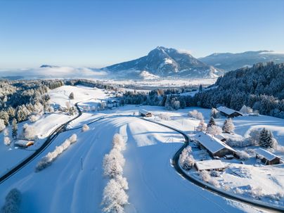 Das Bild zeigt eine Luftaufnahme im Winter von Gunzesried, einem Ortsteil von Blaichach.