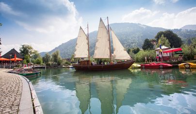 Die Lädine liegt am Bühler Hafen im Wasser, nebenan sind Tretboote zu sehen und ein Berg im Hintergrund 