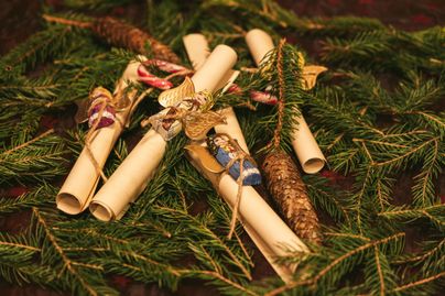 Wunschzettel mit Schokolade-Engel auf Tannenzweigen.