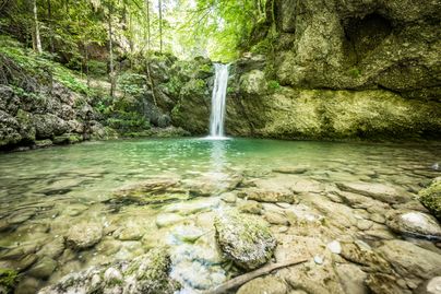 Ein kleiner Wasserfall fließt ins blaue Wasser des Steigbachtobels bei Immenstadt.
