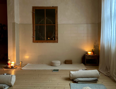Ein ruhiger Raum mit einem Holzfußboden und sanfter Beleuchtung. Genügend Platz für Entspannung mit Sitzkissen und Kerzen.