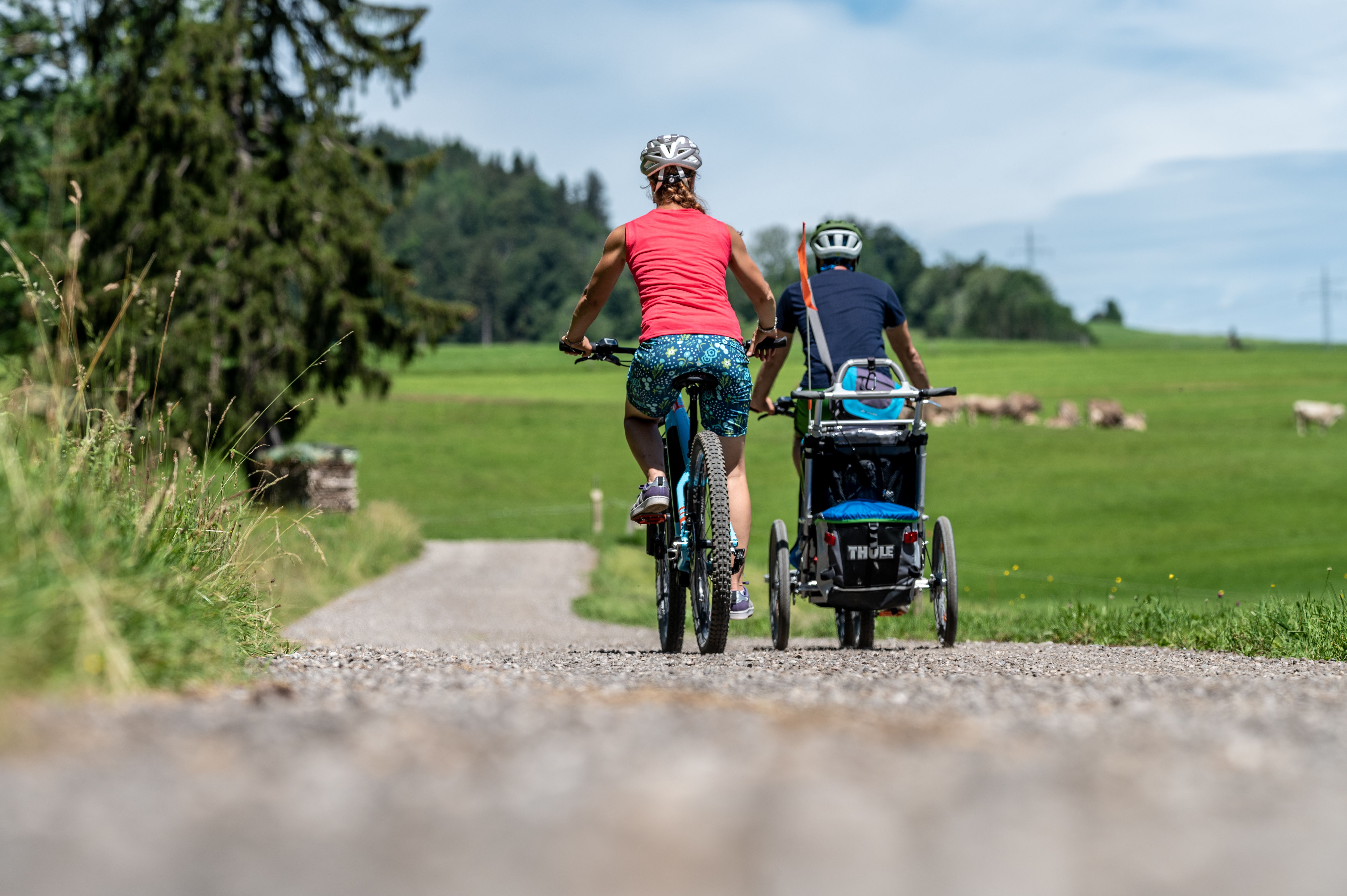 Eine Familie ist im Sommer mit ihren Fahrrädern und dem Fahrradanhänger um den Grünten in Rettenberg unterwegs.