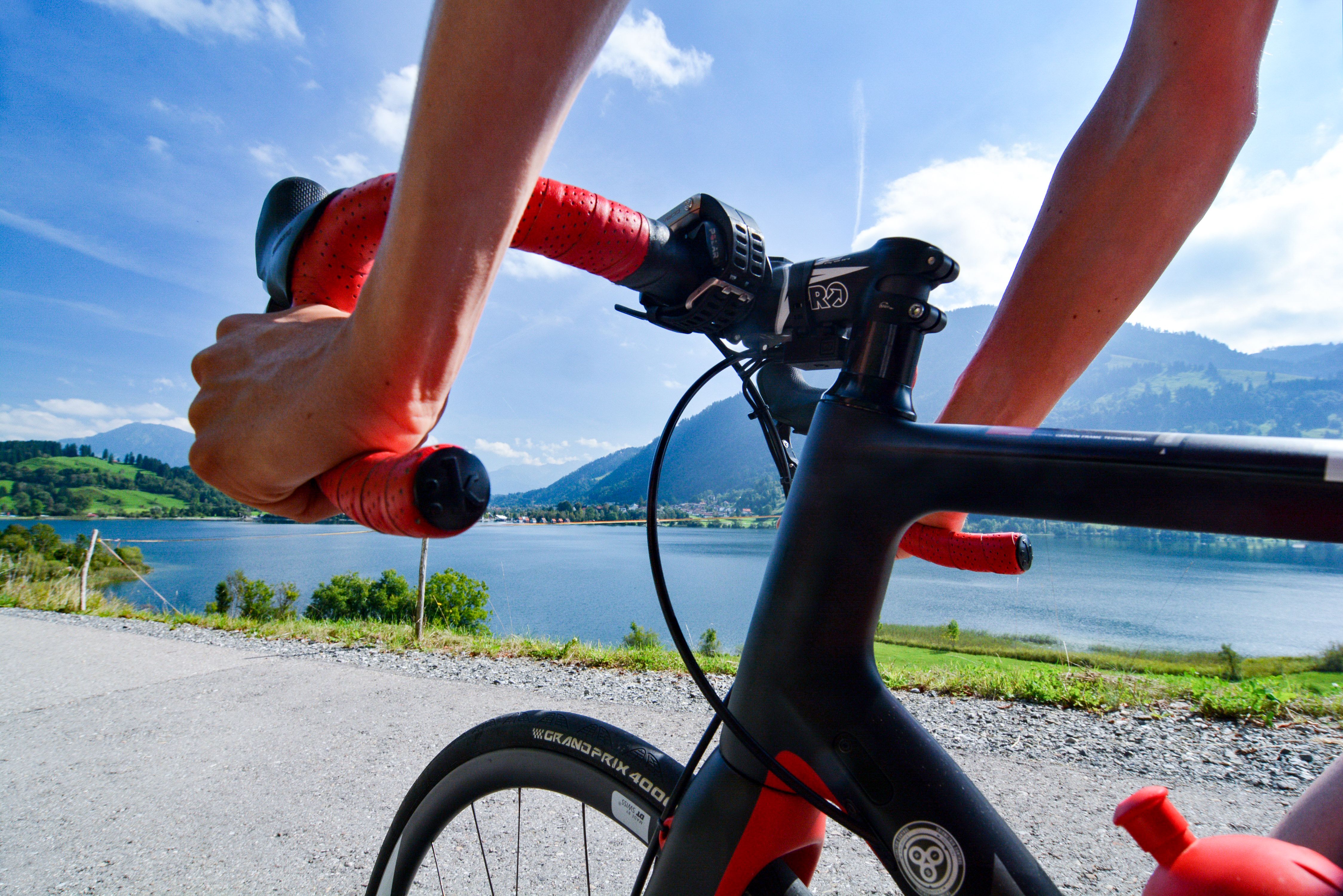 Am Ufer des Alpsees entlang fährt ein Rennradfahrer. Der Alpsee in Immenstadt eignet sich gut als Start für eine Rennradtour.