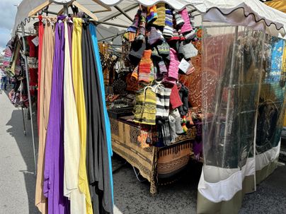 Ein Marktstand mit bunten Schals und handgefertigten Socken. Es gibt viele textile Produkte, die ausgestellt sind.