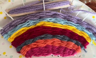 Ein buntes Garn in Form eines Regenbogens. Die Farben verlaufen harmonisch von rot über orange und gelb bis blau und lila.