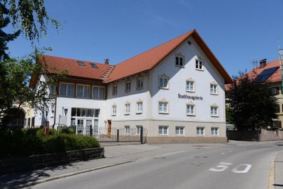 Ein modernes Gebäude mit rotem Dach und weißen Wänden. Es steht an einer ruhigen Straße und scheint ein Gästehaus zu sein.