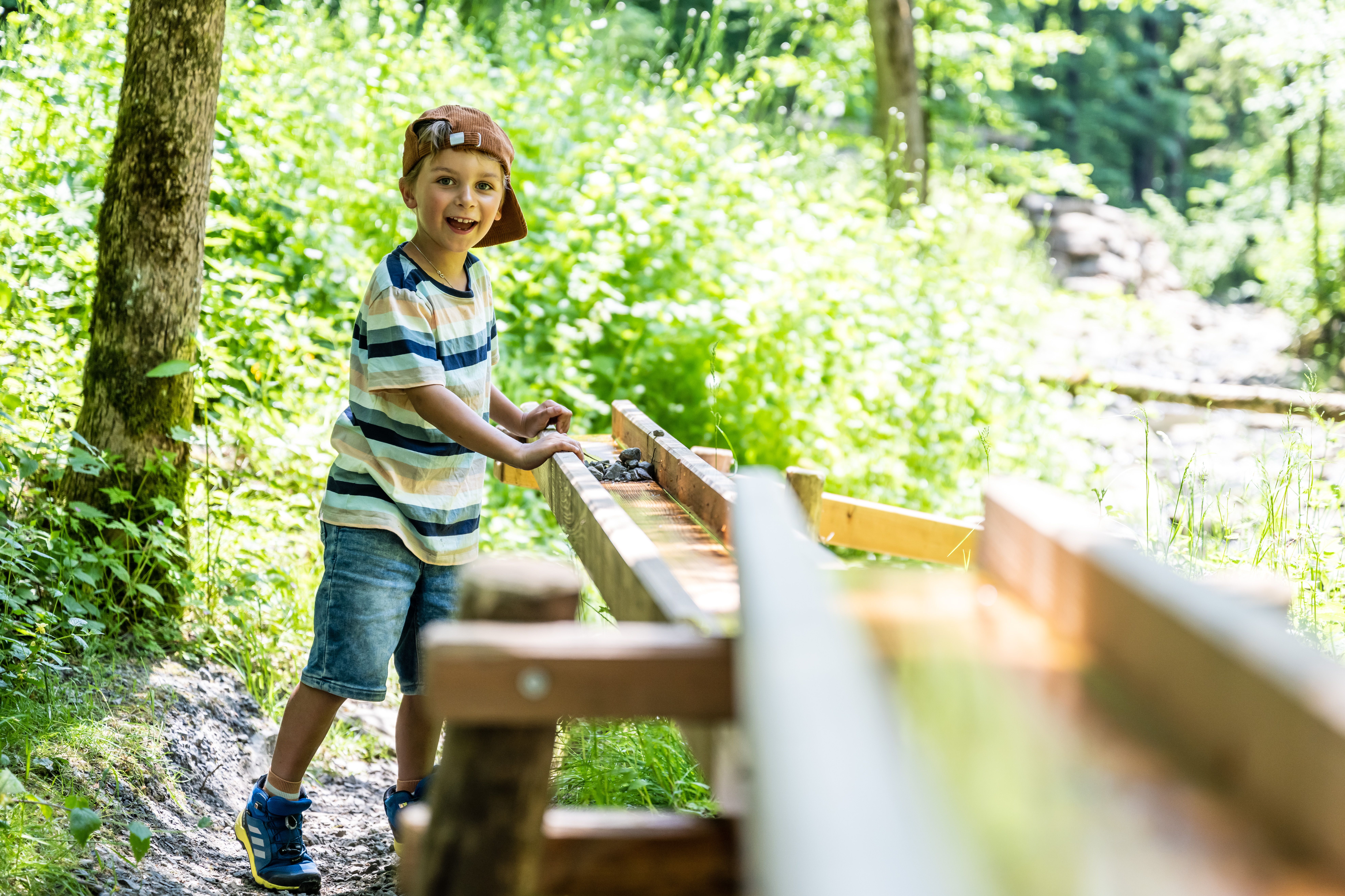 Ein Junge spielt an der Mühle am rauschenden Bach auf der Wanderung "Erlebnispfad Galetschbach".